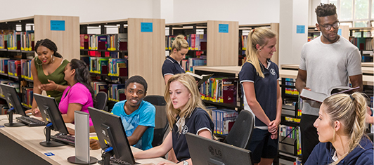 Four smiling students in library.